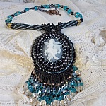Pendentif Angelot avec un cabochon Ange brod&eacute; de perles rondes nacr&eacute;es Cristal avec des rocailles. S&rsquo;ajoute des facettes, toupies, perles ovales Lampwok serti d&rsquo;un ruban Dor&eacute; et palets